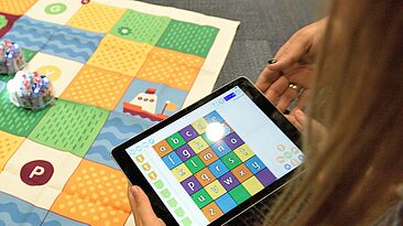 stem-t4l-unsplash Lehrerin hilft einem Kind bei der Benutzung eines Tablets